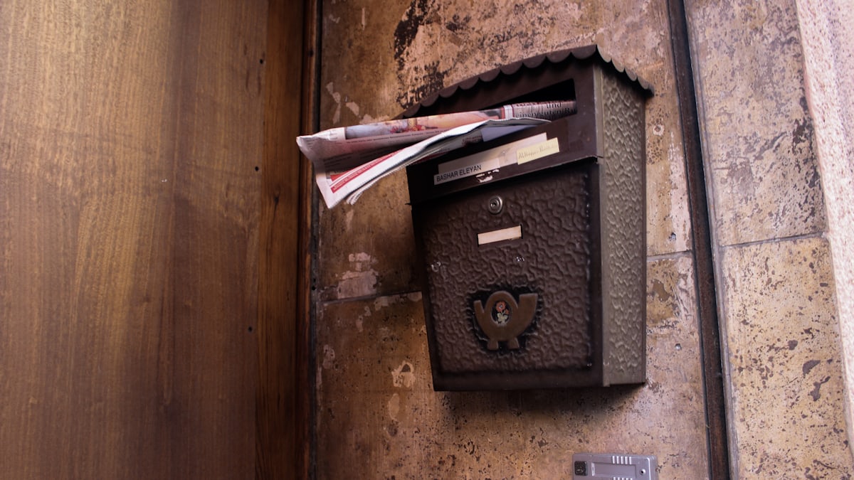 A row of standard grey metal letterboxes on a modern apartment building wall in Germany.