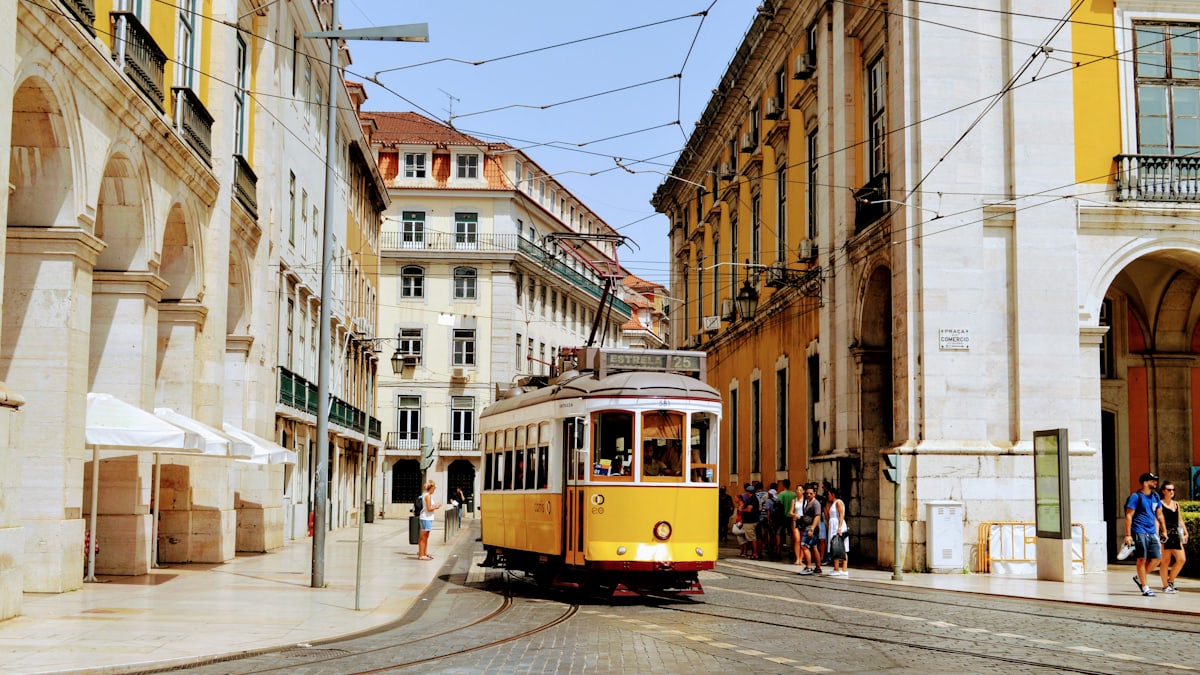 A yellow tram climbing a narrow street in Lisbon