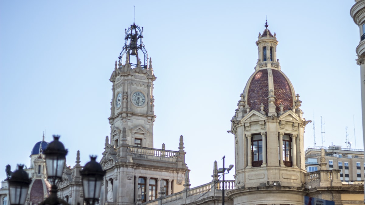 A Spanish town hall building with people waiting outside near the entrance.